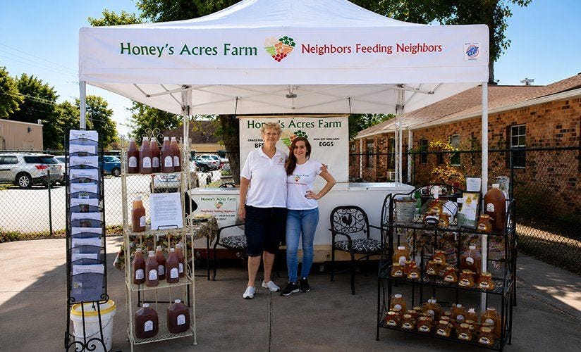 Vendor canopy tent at a farmers market displaying local products, showcasing portable outdoor shelters for street vendors, market stalls, and small businesses.